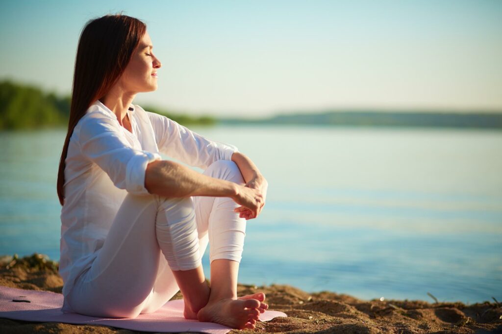 Une femme qui prend une grande respiration devant un lac