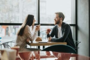 Homme et femme discutant autour d’un café, illustrant les différences entre introverti et extraverti dans les relations sociales